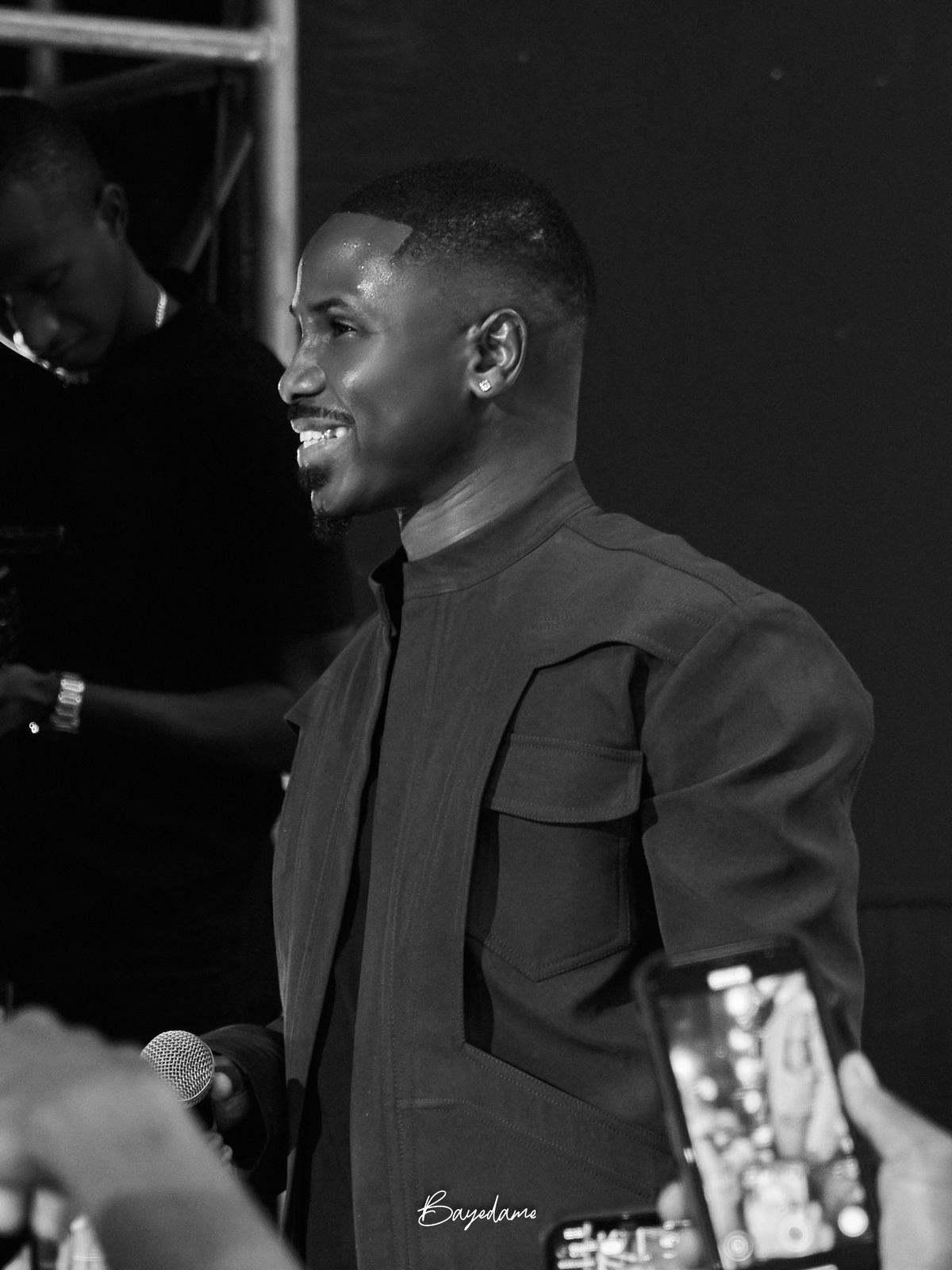 Chanteur souriant en coulisse, noir et blanc — captation concert par Baye Dame