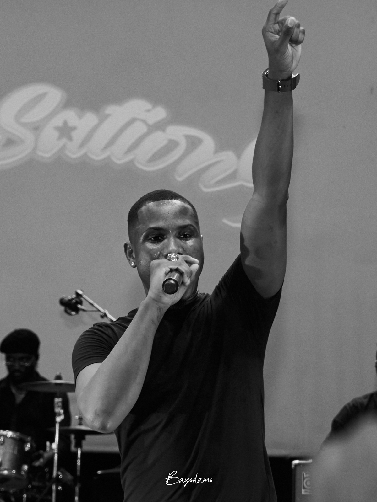 Chanteur au micro, bras levé, noir et blanc — captation concert par Baye Dame